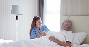 a nurse checking up on an elderly man in bed during the morning