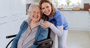 a lady smiling with a disabled elderly lady in a kitchen