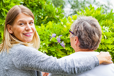 a back view of an elderly lady with a carer looking back towards the camera