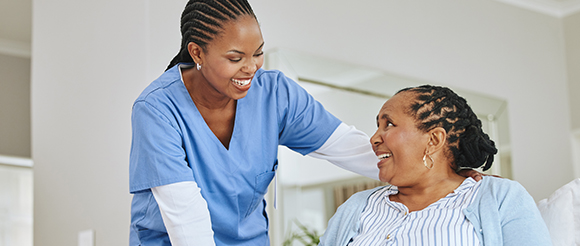 a nurse smiling and holding the shoulder of an elderly lay