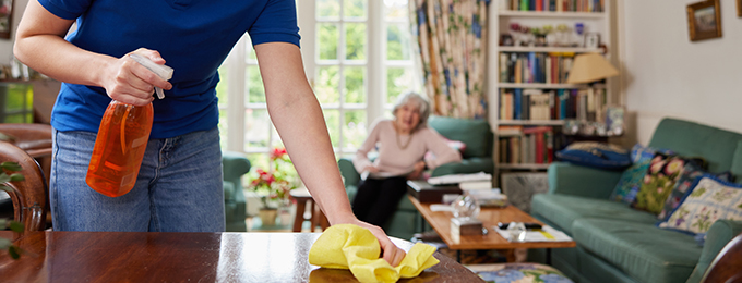 a nurse helping a clean a table in an elderly lady's house