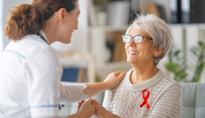 a lady holding the hands of an elderly lady with a ribbon on her clothing